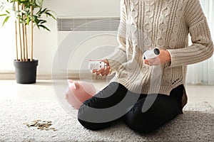 Woman with thermostats and piggy bank at home. Heating saving concept