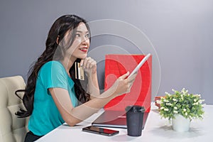Woman thiking and using digital tablet for online shopping with