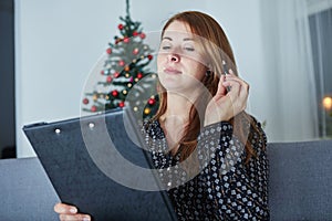 Woman think about christmas wih list on sofa