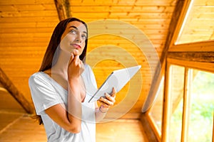Woman thinking with digital tablet in the wooden