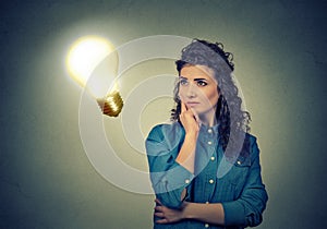 Woman thinking dreaming looking up at bright light bulb