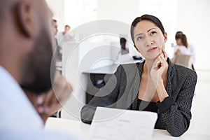 Woman thinking during a job interview in an open plan office