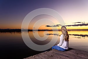 Woman thinks calmly in a beautiful autumn scenery at sunset with warm tones, natural background