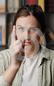 Woman threatens with his finger. Serious frowning woman in office or apartment room interior looking at camera and