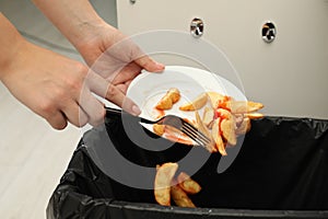 Woman throwing baked potato with ketchup into bin, closeup