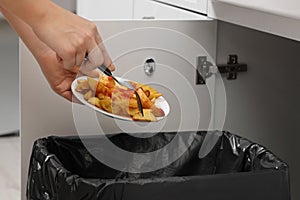 Woman throwing baked potato with ketchup into bin indoors, closeup