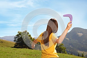 Woman throwing boomerang in mountains, back view. Space for text