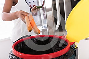 Woman Throwing Carrot In Trash Bin