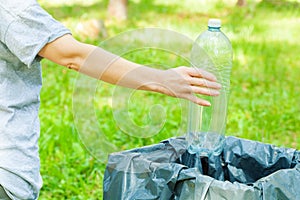 Woman throwing empty plastic water bottle in garbage bin