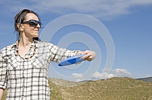 Woman throwing frisbee in sand dunes