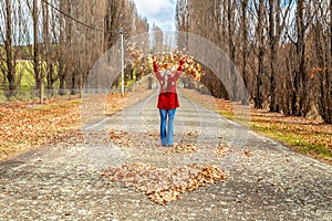 Woman throwing leaves in air in front of heart of fallen leaves Autumn