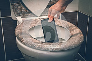 Woman throwing mobile phone in the toilet bowl