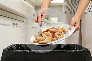 Woman throwing onion rings into bin indoors, closeup