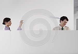 Woman Throwing Paper Aeroplane At Male Colleague