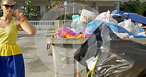 Woman throwing plastic bottle into street garbage