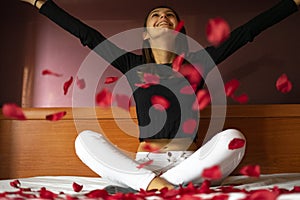 Woman throwing rose petals on the bed