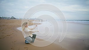 Woman throwing stones water ocean on cloudy day. Thinking girl resting seaside