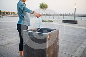 Woman throwing a used surgical face mask in the trash outdoors