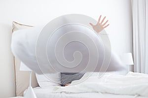 Woman throwing white pillow at camera.