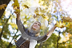 Woman throws autumn leaves in park