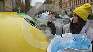 Woman throws plastic waste at a recycling point outdoors