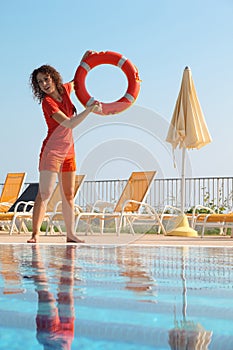 Woman throws red buoy ring to pool