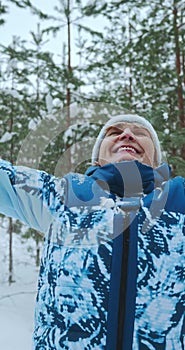 a woman throws snowflakes with her hands up and rejoices in the falling snow