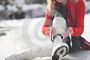 Woman tie shoelaces figure skates at ice rink close-up