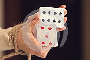 Woman with tied hands holding playing cards, closeup