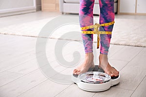 Woman tied with tape measuring her weight using scale