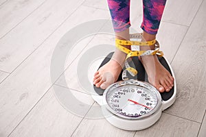 Woman tied with tape measuring her weight using scales