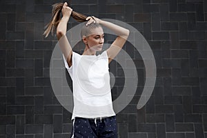 Woman Ties her hair in a ponytail before morning workout black wall background