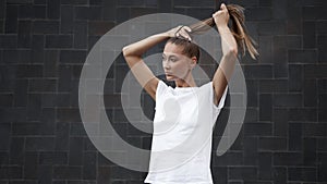 Woman Ties her hair in a ponytail before morning workout black wall background