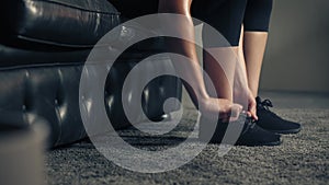 Woman ties her shoes before starting workout at home or gym. Active woman tying up shoelaces during training.legs and