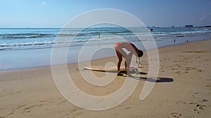 Woman ties surfboard rope to leg against pictorial seascape