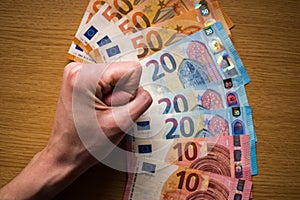 Woman tight fist and money on wooden background