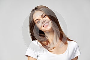 Woman tilted her head to the side And smiling on a light background close-up