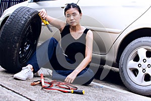 A woman is tired after checking tyre of car