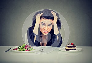 Woman tired of diet restrictions deciding to eat healthy food or cake she is craving