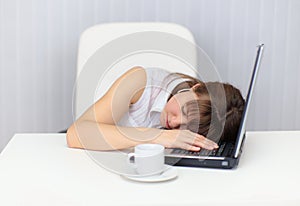 Woman tired and fell asleep at table with a laptop