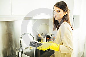 Woman tired of hand washing and cleaning chores.Housewife woman washing dishes in kitchen. Washing dishes manually, wearing yellow