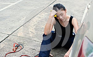 A woman is so tired after repairing car