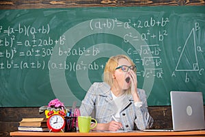 Woman tired teacher sit table classroom chalkboard background. Working conditions for teachers. Work far beyond the