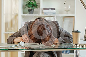 The woman is tired. Young tired woman put her head on the table, tired worker or student sitting exhausted on the table