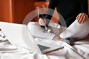 Woman toasting with a glass of wine by video call.