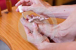 Woman toe nails polish with foot on wooden chair