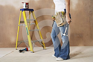 Woman With Toolbelt And Hammer Leaning Against Wall photo