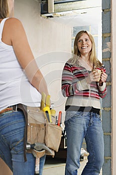 Woman With Toolbelt Talking To Smiling Female