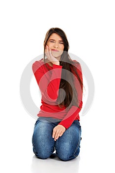 Woman with toothache sitting on the floor.