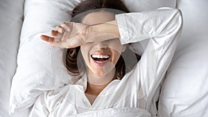 Woman with toothy smile wokeup after sleeping lying in bed